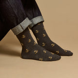 Le modèle porte des chaussettes mi-hautes grises à motifs jaunes, fantaisie pour homme.